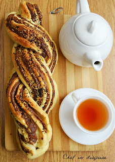 braided date bread on wooden table with teapot and teacup beside