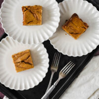 overhead view of three white plates with pumpkin cheesecake bars