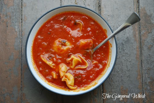 bowl of tomato basil soup with cheese tortellini and spoon
