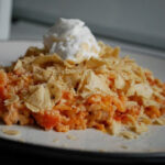 ground turkey mexican casserole on plate with crushed tortilla chips and sour cream