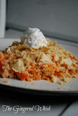 ground turkey mexican casserole on plate with crushed tortilla chips and sour cream