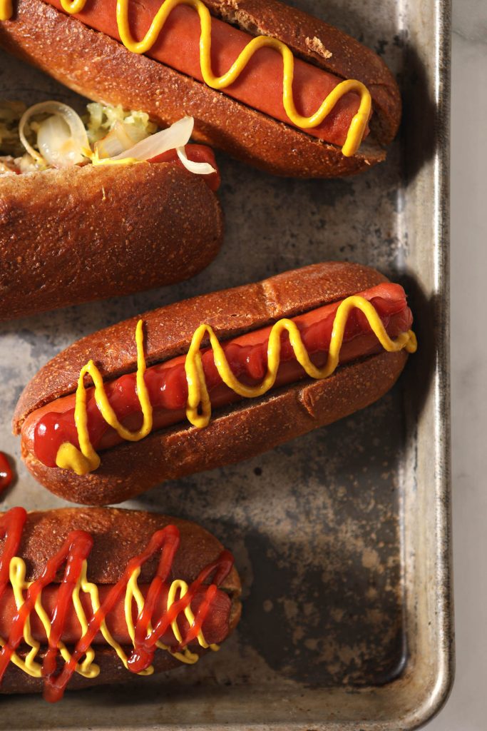 three buns with hot dogs  on baking tray
