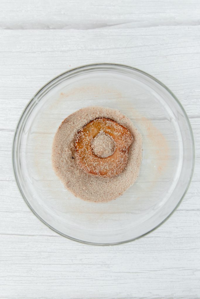 glass bowl with fried apple ring being tossed in cinnamon sugar