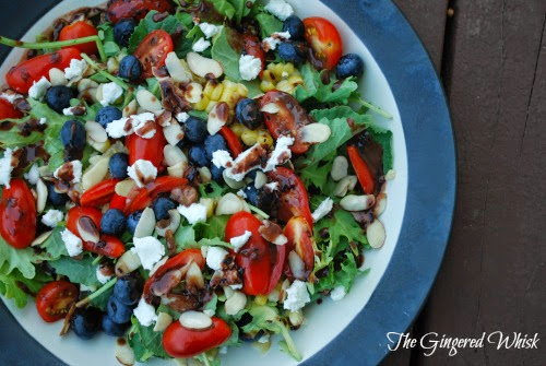plate with salad filled with blueberries, tomatoes, and balsamic dressing