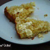piece of sourdough cornbread split open with honey and butter on plate