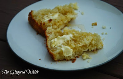 piece of sourdough cornbread split open with honey and butter on plate