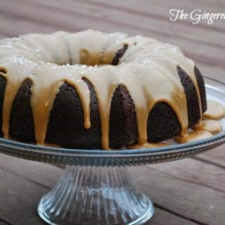 chocolate bundt cake on glass cake plate with caramel icing dripping down