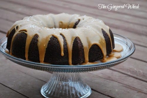 chocolate bundt cake on glass cake plate with caramel icing dripping down