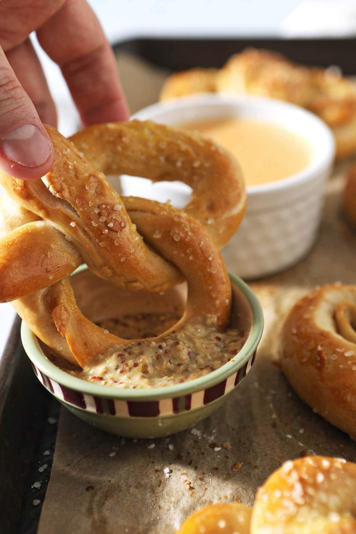 dipping sourdough pretzel into mustard dip