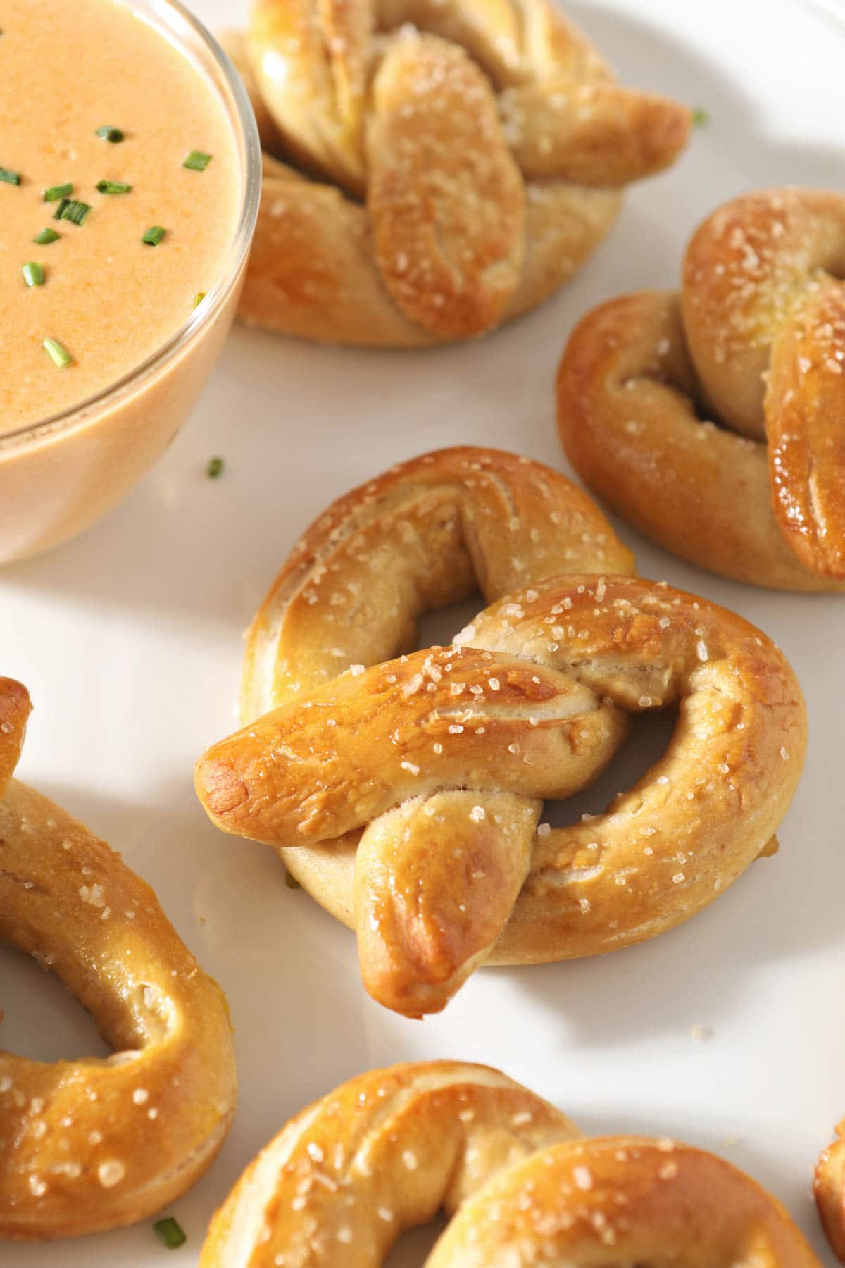 close up of sourdough pretzel next to cheese dip