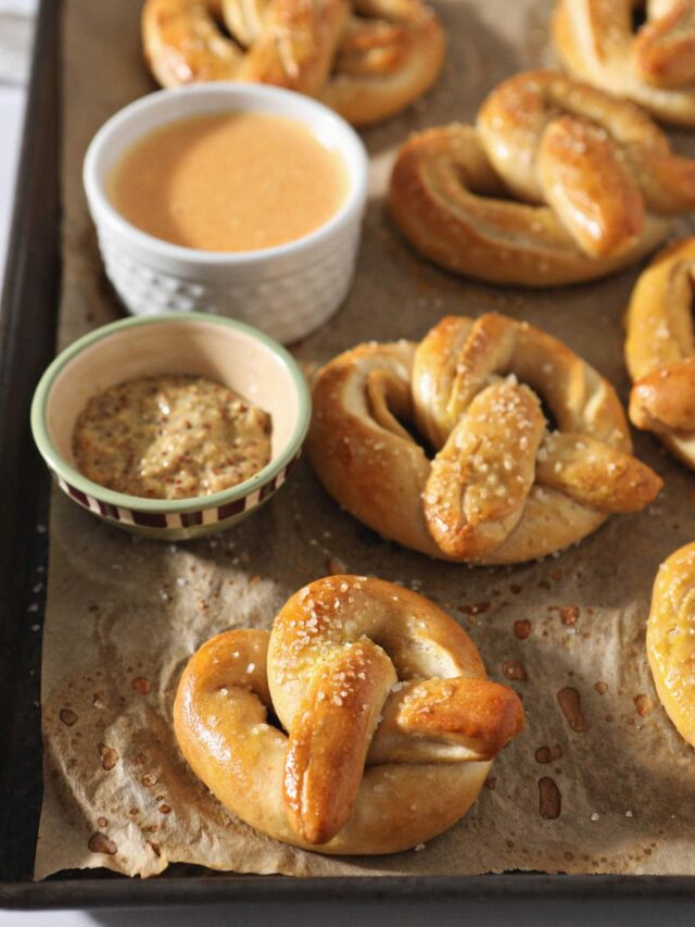 freshly baked pretzels beside honey mustard and cheese dip