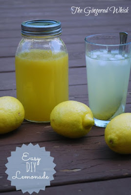 pitcher of lemonade concentrate next to glass with lemons around 