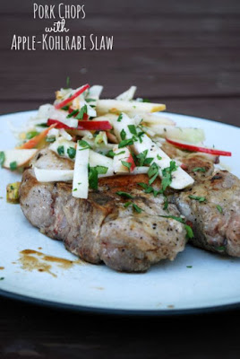 two pork chops on plate topped with apple kholrabi slaw