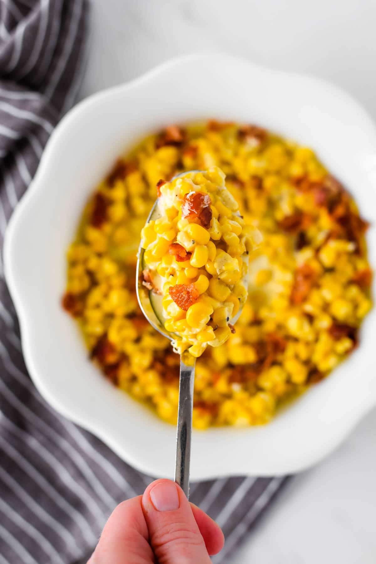 spoon with creamed corn over bowl