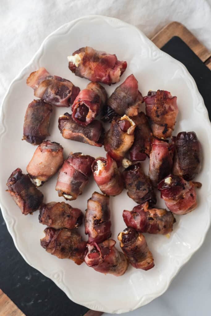 bacon wrapped dates on white platter