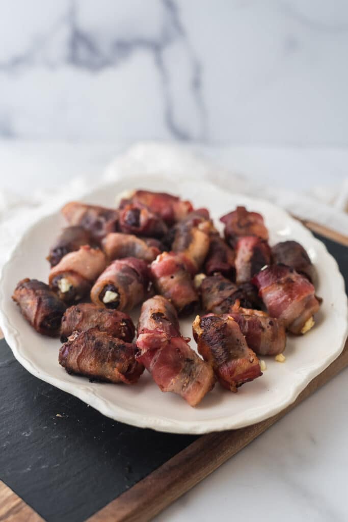 white platter with bacon wrapped dates piled on