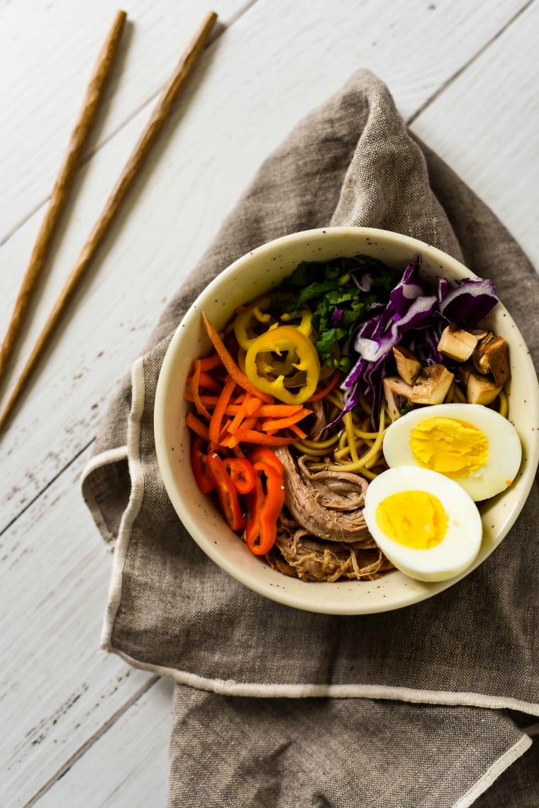 bowl of pork ramen on grey napkin beside chopsticks