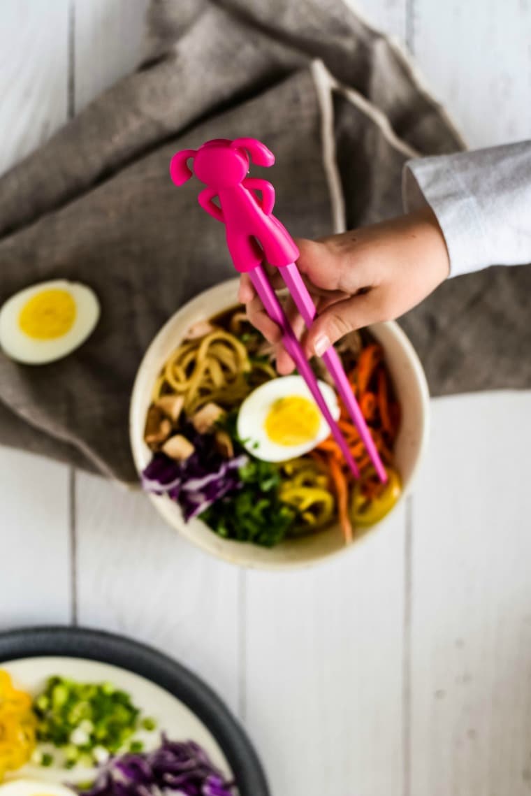 Girl using chopsticks with ramen