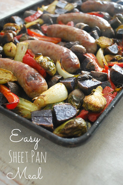 baking sheet with bratwurst, onions, peppers, potatoes and brussels spouts 