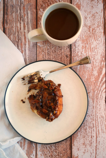 chocolate pecan sticky roll with cup of coffee