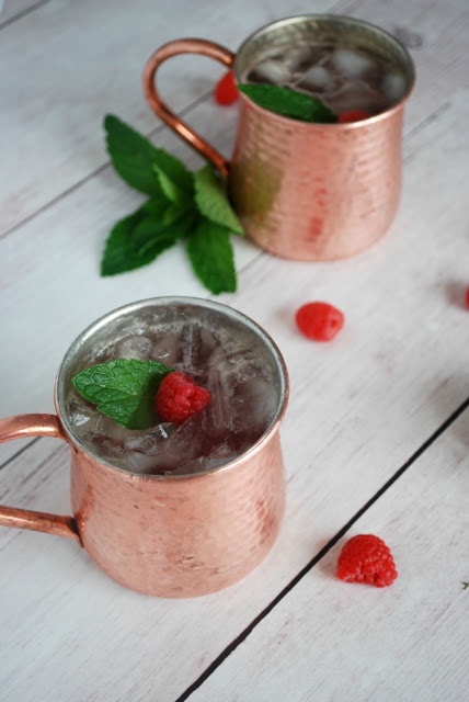 two moscow mule mugs with raspberry mules and mint