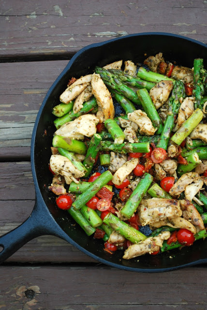 A cast iron skillet with pesto chicken and veggies inside