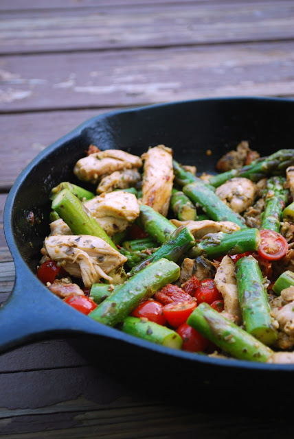 A cast iron skillet with skillet pesto chicken on a wooden table