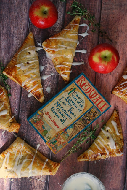 A wooden table with a book, apple, and apple turnovers