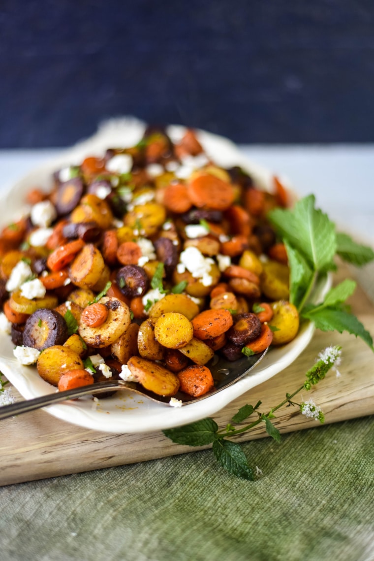 roasted rainbow carrots on white platter with spoon