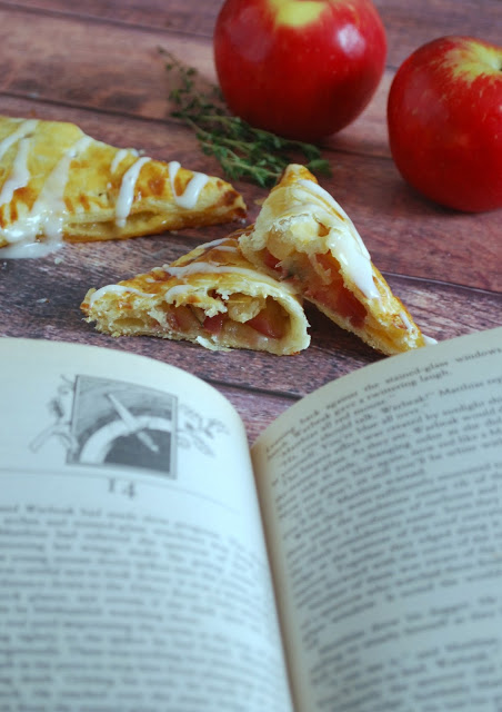 An open book with apple turnovers, apples, and fresh thyme in the background 