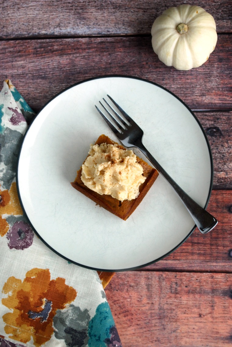 A white plate with a fork and a piece of pumpkin maple gingerbread cake on a wooden table with a fall napkin
