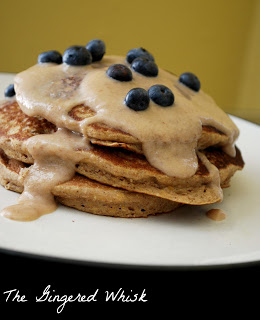 A white plate with a stack of pumpkin spice pancakes topped with a maple cream syrup and blueberries