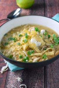 white chicken chili in bowl with sour cream and tortilla strips