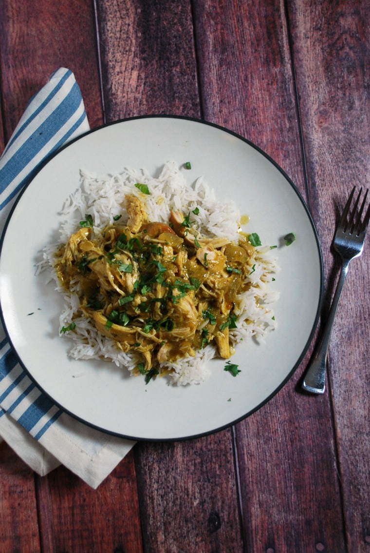 A white plate on a blue and white striped napkin with a serving of rice and coconut chicken curry