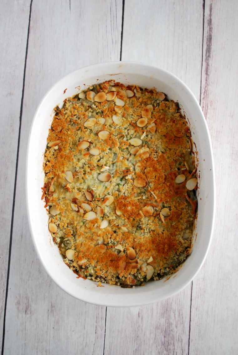 A white serving dish of green bean casserole on a white wooden table