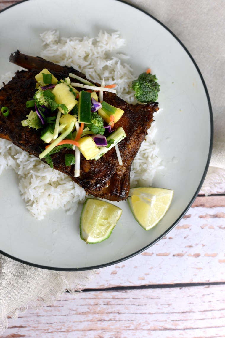 A plate on a wooden table with Thai turmeric ribs and rice