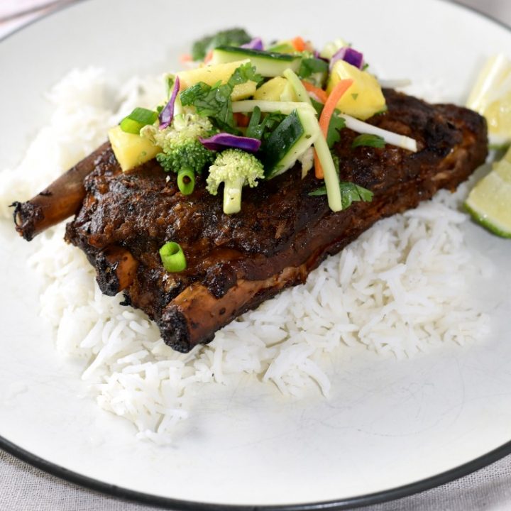 A white plate with Thai turmeric ribs, rice, and pineapple slaw 