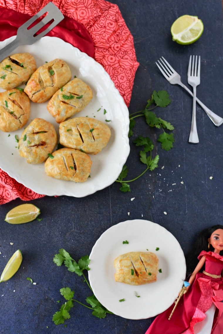 A grey slate topped with beef empenadas and a Princess Elena doll