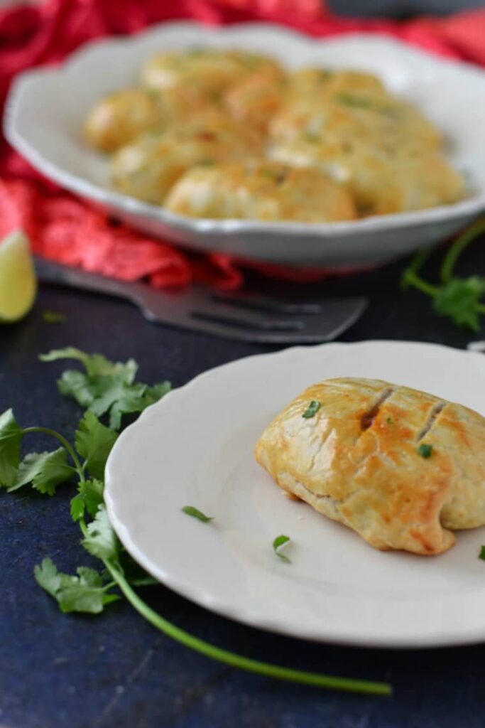 A plate with a beef empanada with fresh herbs on the table