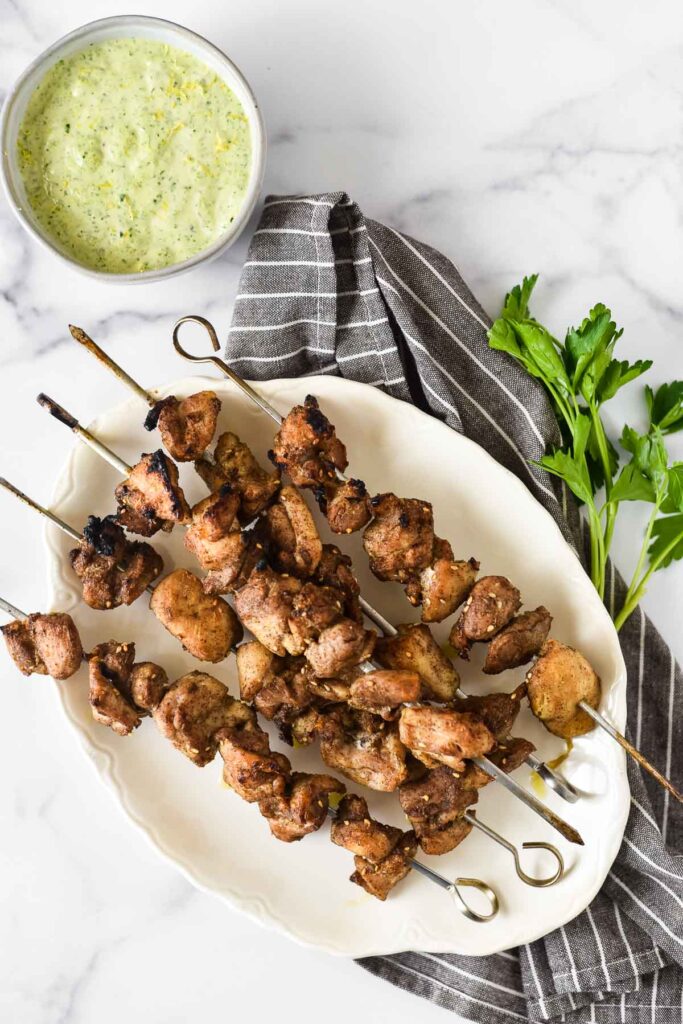 chicken skewers on a plate with tahini sauce beside