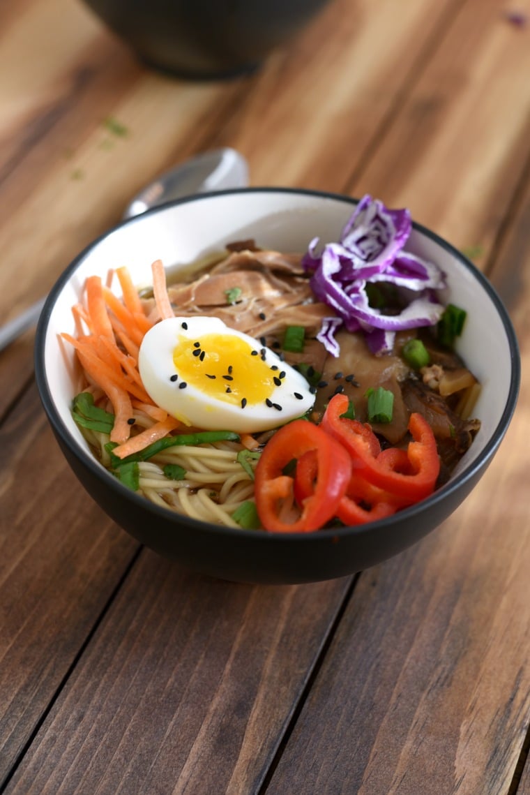 A bowl of crock pot chicken ramen on a wooden table