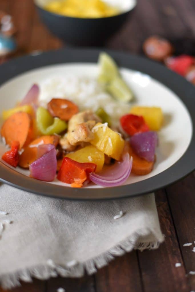 A black and white bowl of Polynesian chicken on a wooden table