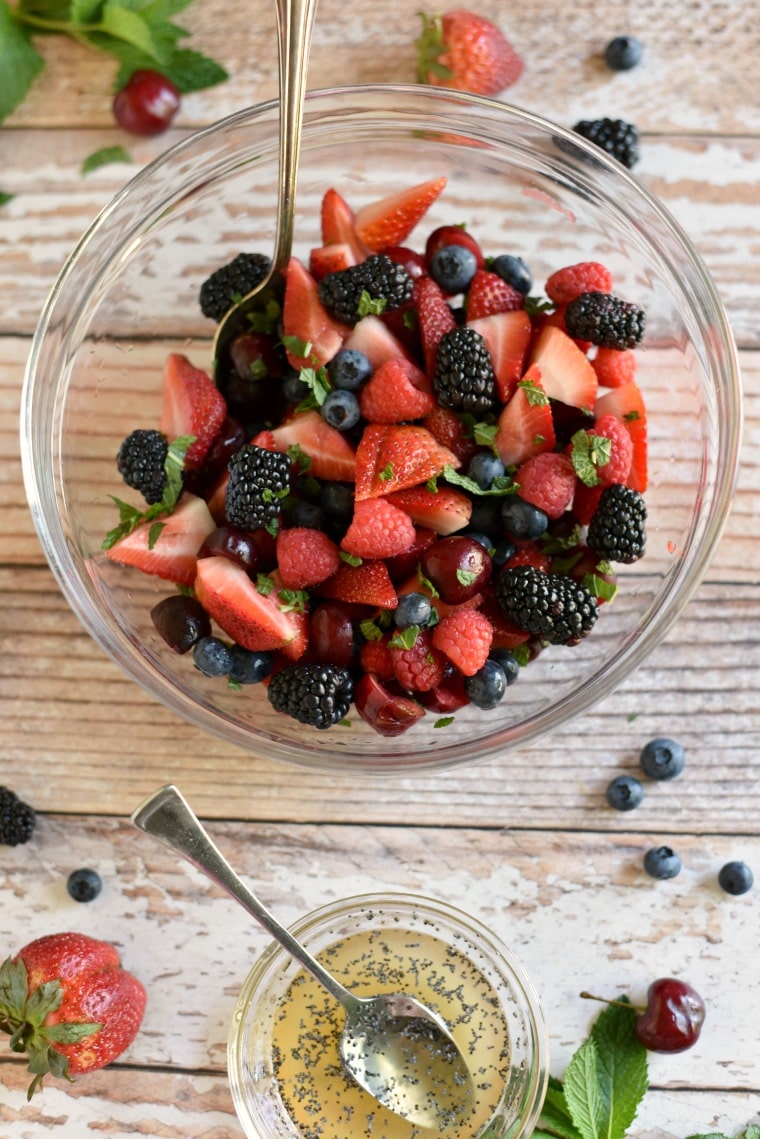 A clear bowl on a wooden table with berry fruit salad