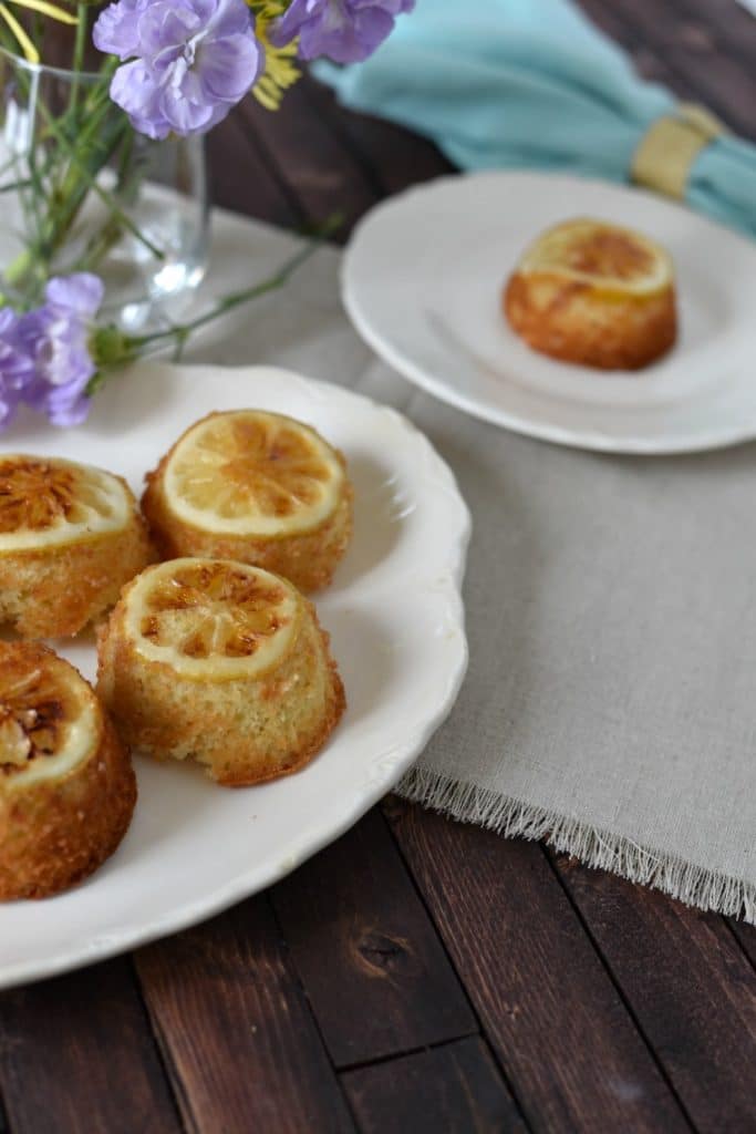 Two plates of lemon cakes on  a white napkin with flowers 