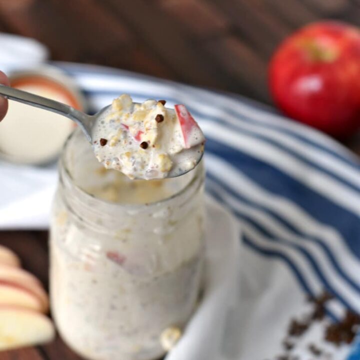 A spoon lifting a bite of apple pie overnight oats out of a mason jar