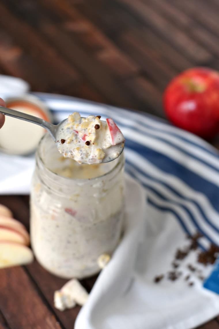 A spoon lifting a bite of apple pie overnight oats out of a mason jar