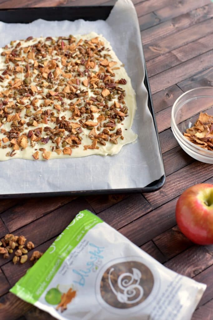 A wooden table with a pan of apple cinnamon white chocolate bark 