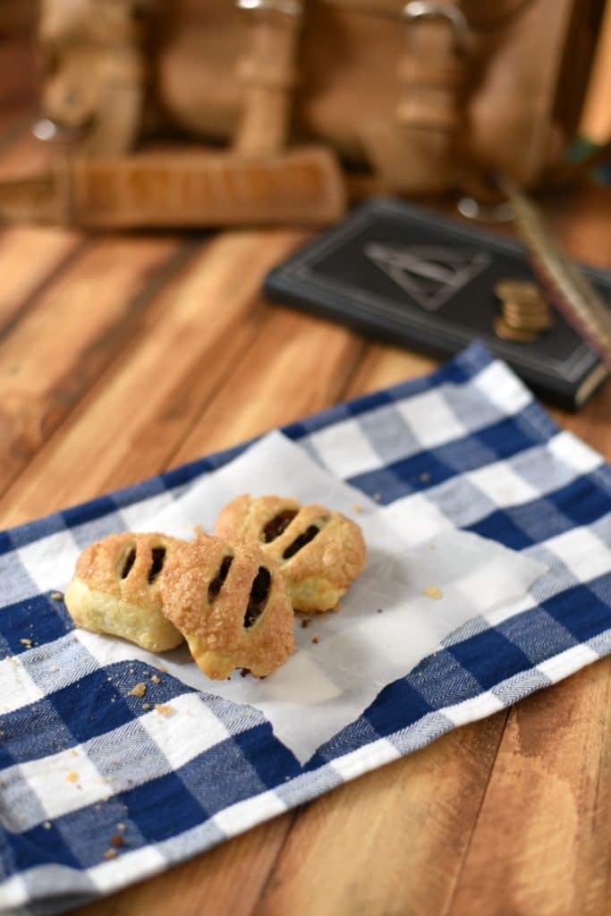 Three cauldron cakes on a white and blue napkin with a book in the background 