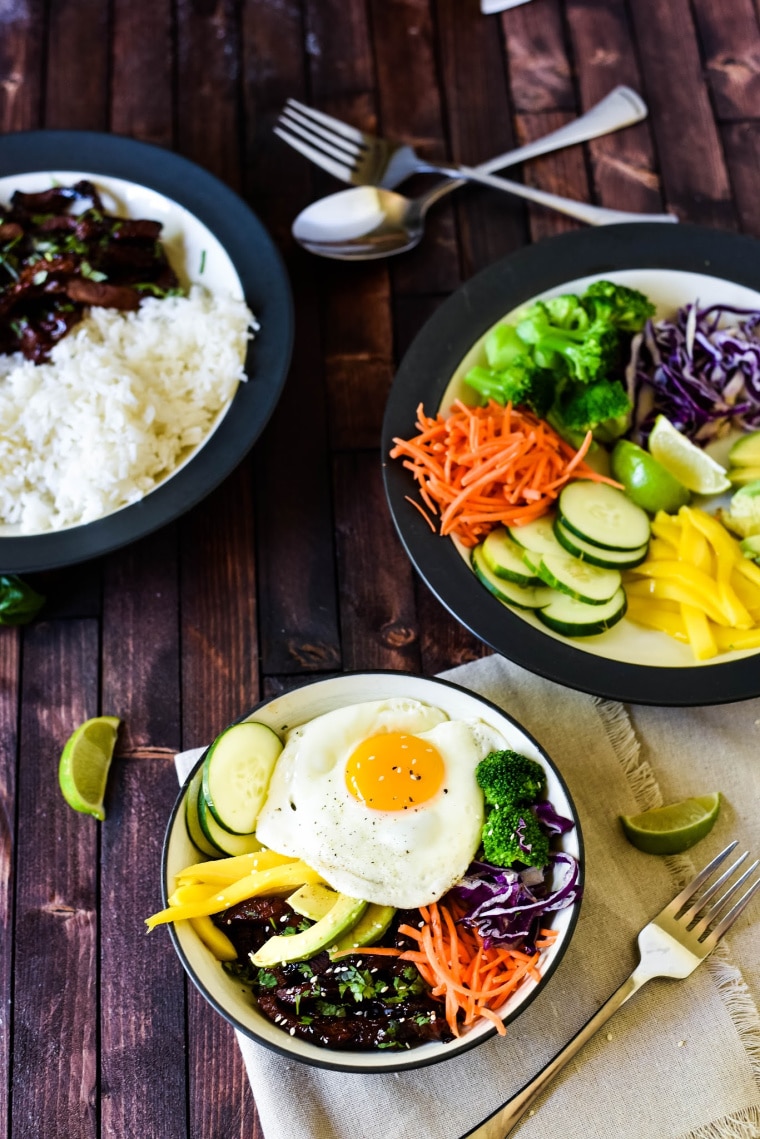 A bowl of veggies, a bowl of rice and meat, and an assembled bowl of Korean beef bulgogi with a fried egg