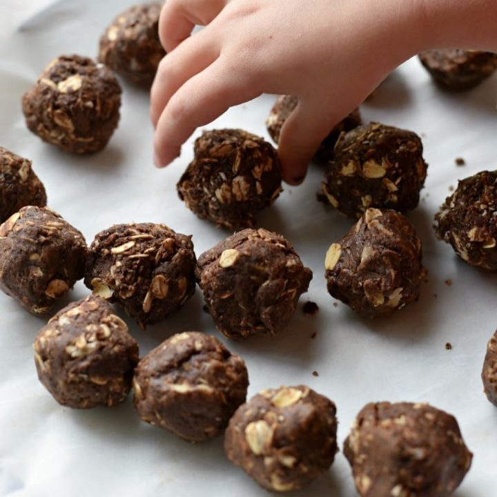 A child reaching for a plate of chocolate peanut butter energy balls 